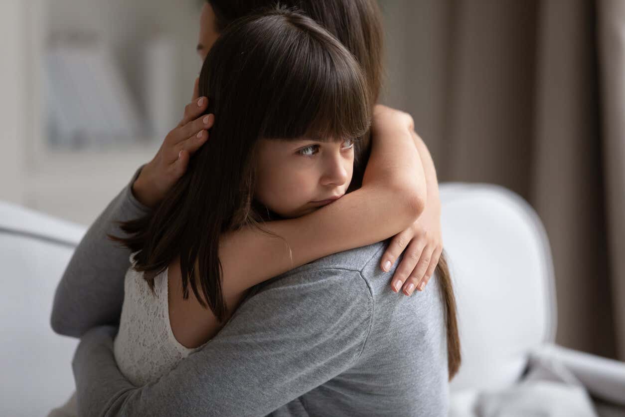 A menina recebe um abraço da mãe. Anexo seguro.