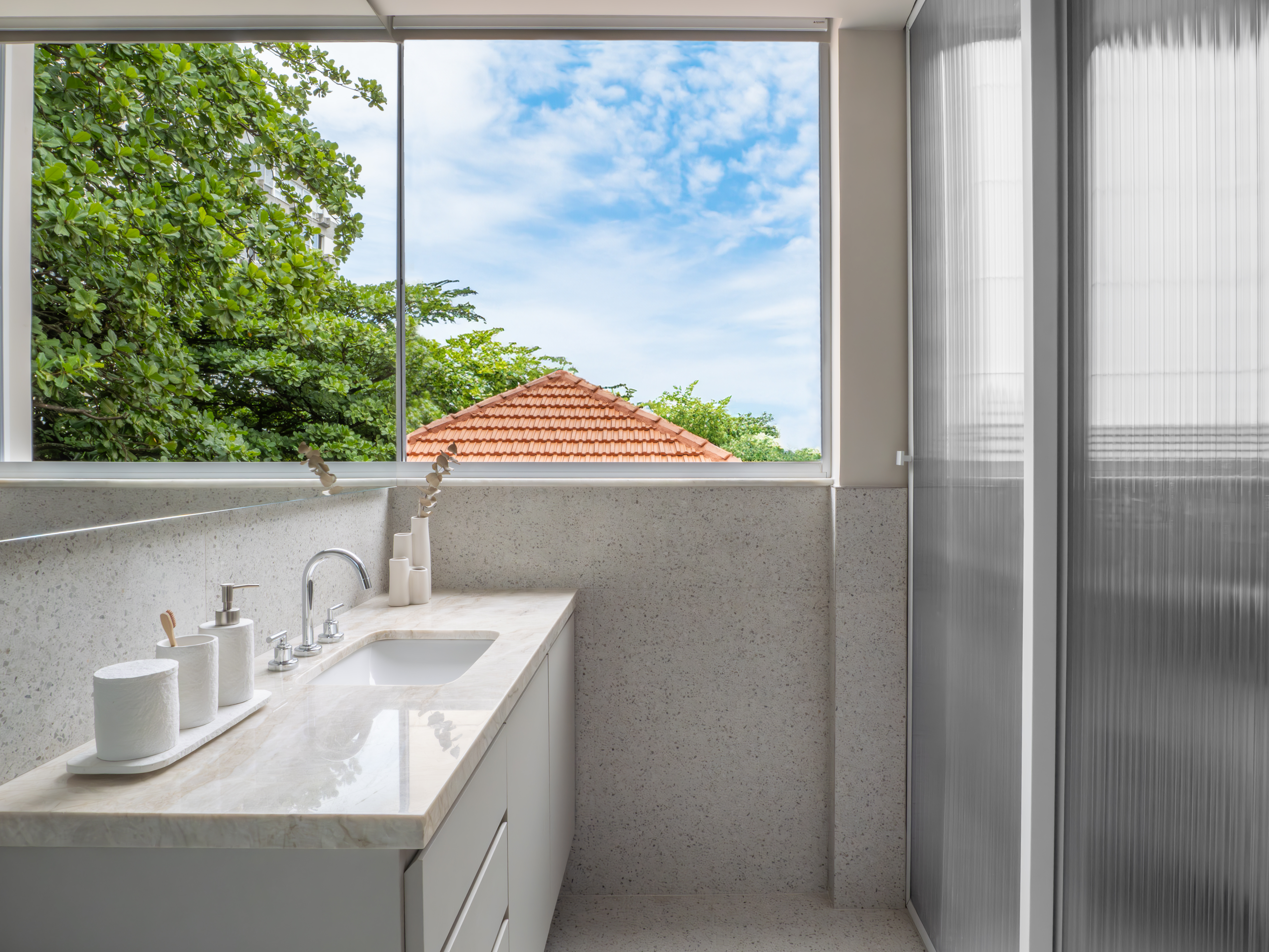 Apartamento-Leblon-Gabriella-Machado-06 Banheiro com porcelanato que simula granilite, espelho estratégico e iluminação natural, inspirado no design clássico da Bahia