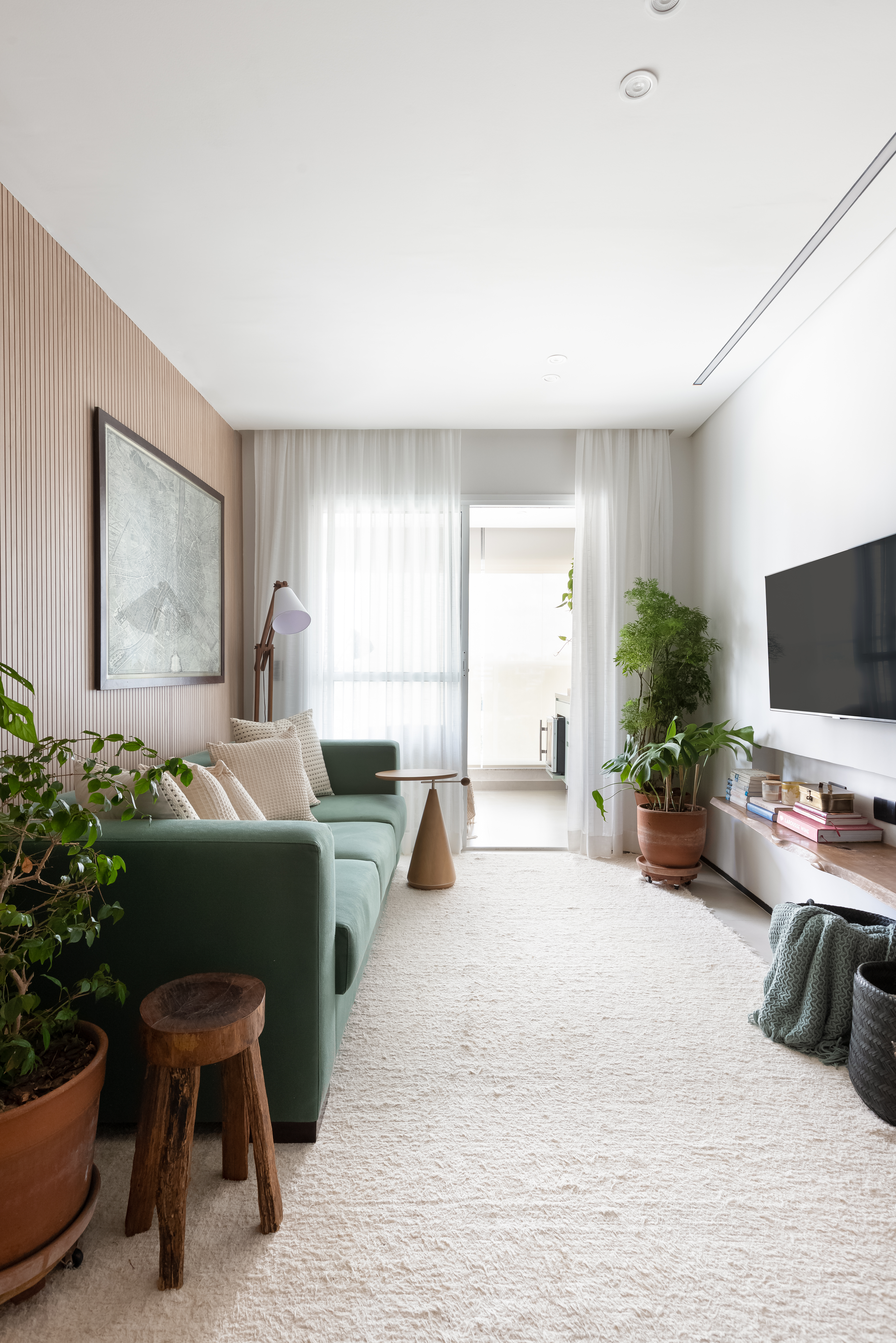 sala integrada com painel ripado ocultando portas íntimas.