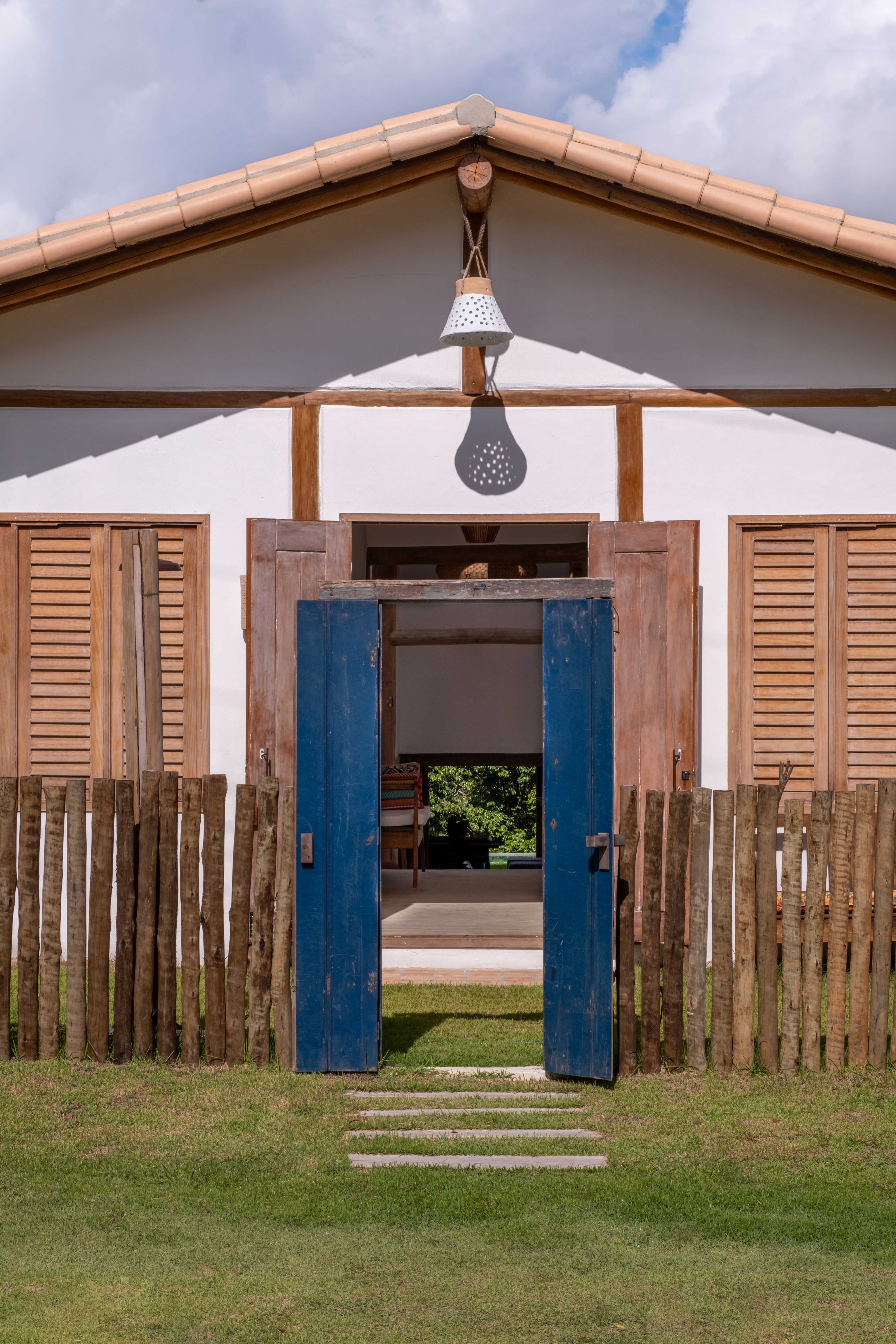 Fachada de casa em Trancoso com telhado contínuo, madeira aparente e integração ao terreno em declive